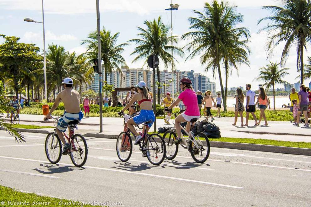 Imagem com coqueiros na orla, prédios e pessoas praticando esportes na Praia de Cambori.